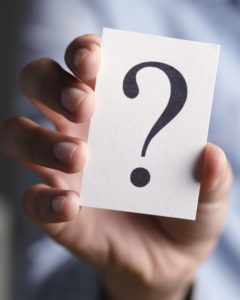 A young woman holding a card with a question mark.